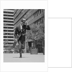 Businessman carrying briefcase holding his hat on running down urban sidewalk by Anonymous