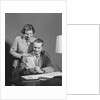 Couple man seated at desk holding paper woman standing looking over his shoulder smiling happy by Anonymous
