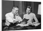 Couple man woman smiling looking at banking savings passbook at home desk by Anonymous