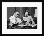 Couple man woman smiling looking at banking savings passbook at home desk by Anonymous