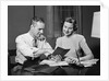 Couple man woman smiling looking at banking savings passbook at home desk by Anonymous