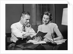 Couple man woman smiling looking at banking savings passbook at home desk by Anonymous