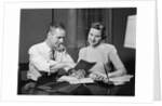 Couple man woman smiling looking at banking savings passbook at home desk by Anonymous