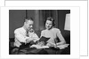 Couple man woman smiling looking at banking savings passbook at home desk by Anonymous