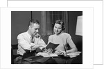Couple man woman smiling looking at banking savings passbook at home desk by Anonymous