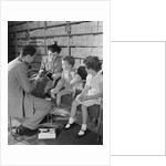 Family mother two children in shoe store trying new shoes helped by salesman by Anonymous