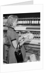 Blond woman selecting ice cream frozen food section supermarket by Anonymous