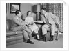 Couple sitting on couch talking to smiling insurance salesman handing them a policy by Anonymous