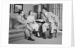 Couple sitting on couch talking to smiling insurance salesman handing them a policy by Anonymous