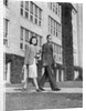 College couple walking on campus before ivy covered building by Anonymous