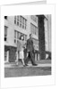 College couple walking on campus before ivy covered building by Anonymous