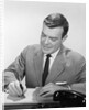 Smiling businessman at desk writing checks by Anonymous