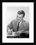 Smiling businessman at desk writing checks by Anonymous