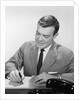 Smiling businessman at desk writing checks by Anonymous