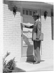 Salesman wearing suit tie hat carrying briefcase ringing suburban house doorbell by Anonymous