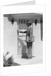 Salesman wearing suit tie hat carrying briefcase ringing suburban house doorbell by Anonymous