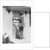 Salesman wearing suit tie hat carrying briefcase ringing suburban house doorbell by Anonymous