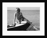 Woman wearing one piece bathing suit sitting on edge of boat by Anonymous