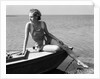 Woman wearing one piece bathing suit sitting on edge of boat by Anonymous
