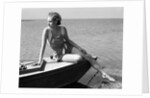 Woman wearing one piece bathing suit sitting on edge of boat by Anonymous