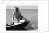 Woman wearing one piece bathing suit sitting on edge of boat by Anonymous