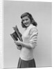 Smiling brunette teen student wearing sweater carrying school books by Anonymous