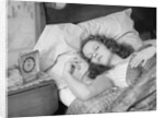 Woman sleeping asleep in bed alarm clock on night table by Anonymous