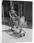 Smiling woman pushing grocery cart out of supermarket by Anonymous
