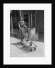Smiling woman pushing grocery cart out of supermarket by Anonymous