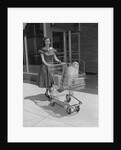 Smiling woman pushing grocery cart out of supermarket by Anonymous