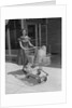 Smiling woman pushing grocery cart out of supermarket by Anonymous
