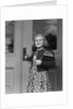 Smiling girl print dress holding school books opening door by Anonymous