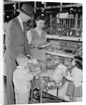 Family of 4 inside supermarket father pushing cart mother 2 kids by Anonymous