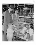 Family of 4 inside supermarket father pushing cart mother 2 kids by Anonymous