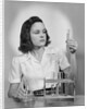 Young woman chemist holding up test tube by Anonymous