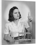 Young woman chemist holding up test tube by Anonymous