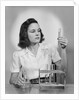 Young woman chemist holding up test tube by Anonymous