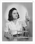 Young woman chemist holding up test tube by Anonymous