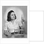 Young woman chemist holding up test tube by Anonymous