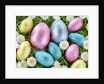 Chocolate Easter eggs in coloured foil in grass by Anonymous
