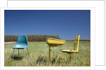Abandoned school desk anc chairs in field by Anonymous
