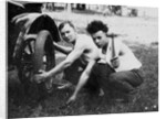 Young men change a tire on an automobile, ca. 1918 by Corbis