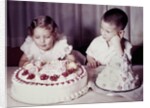Brother watches his sister blow out candles on birthday cake, ca. 1956 by Anonymous
