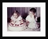 Brother watches his sister blow out candles on birthday cake, ca. 1956 by Anonymous
