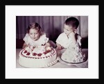Brother watches his sister blow out candles on birthday cake, ca. 1956 by Anonymous