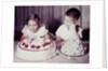 Brother watches his sister blow out candles on birthday cake, ca. 1956 by Anonymous
