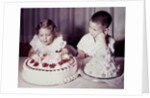 Brother watches his sister blow out candles on birthday cake, ca. 1956 by Anonymous