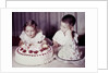 Brother watches his sister blow out candles on birthday cake, ca. 1956 by Anonymous