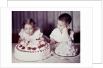 Brother watches his sister blow out candles on birthday cake, ca. 1956 by Anonymous