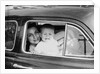 Mother holds crying son in her lap in car, ca. 1954 by Anonymous